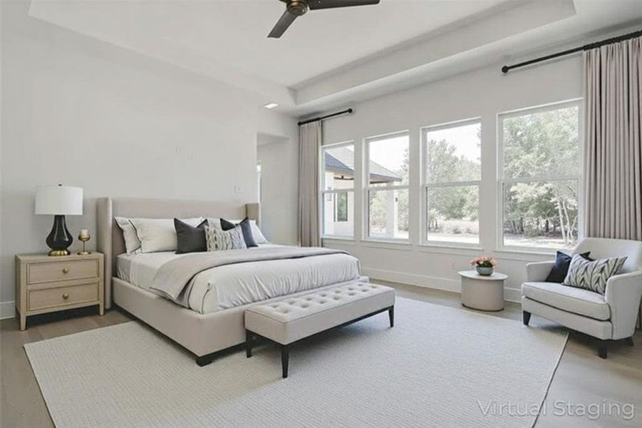 Bedroom with light wood-style flooring, a tray ceiling, and a ceiling fan Bedroom with light wood-style flooring, a tray ceiling, and a ceiling fan