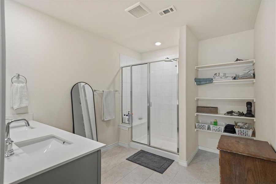 Bathroom featuring double vanity, a stall shower, and light tile patterned floors Bathroom featuring double vanity, a stall shower, and light tile patterned floors