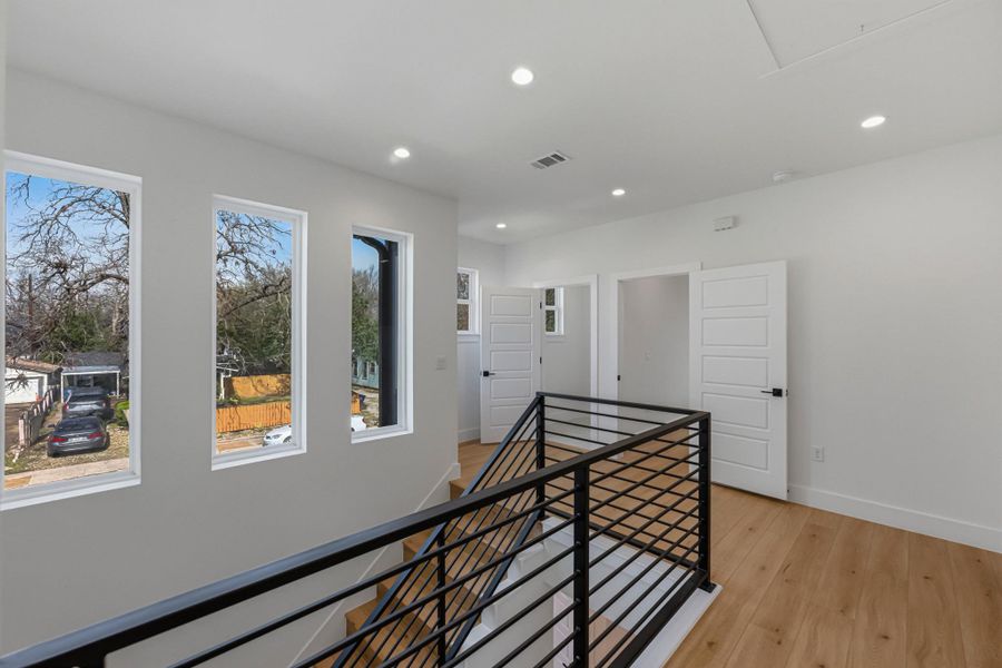 Hallway with an upstairs landing, light wood-style flooring, and recessed lighting