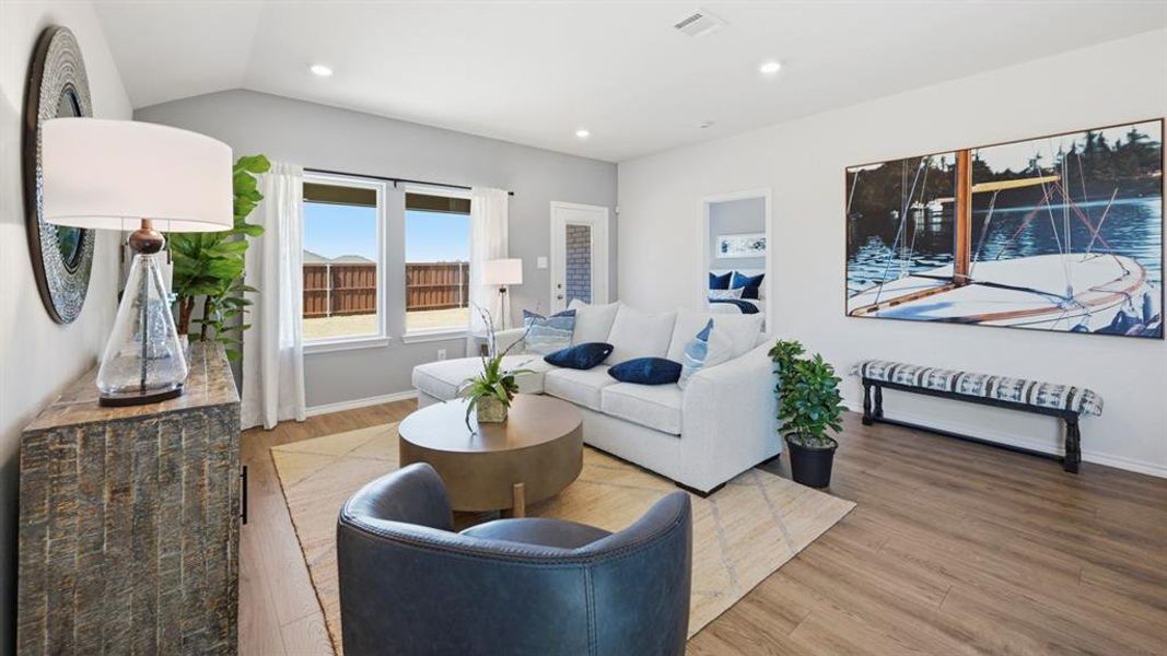 The living area features vaulted ceilings, recessed lighting, and large windows providing natural light