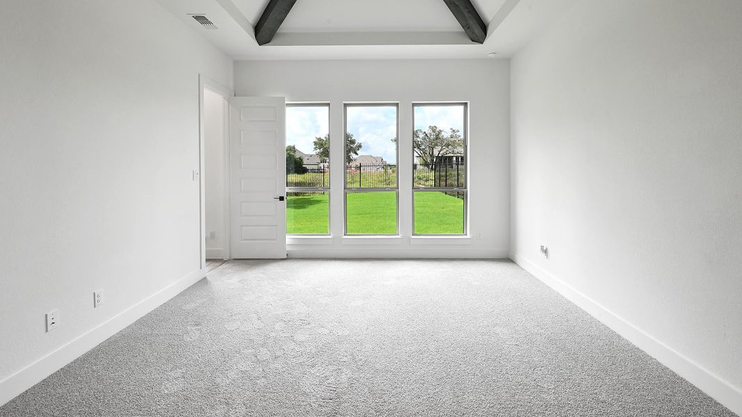 Carpeted empty room with beam ceiling and baseboards Carpeted empty room with beam ceiling and baseboards