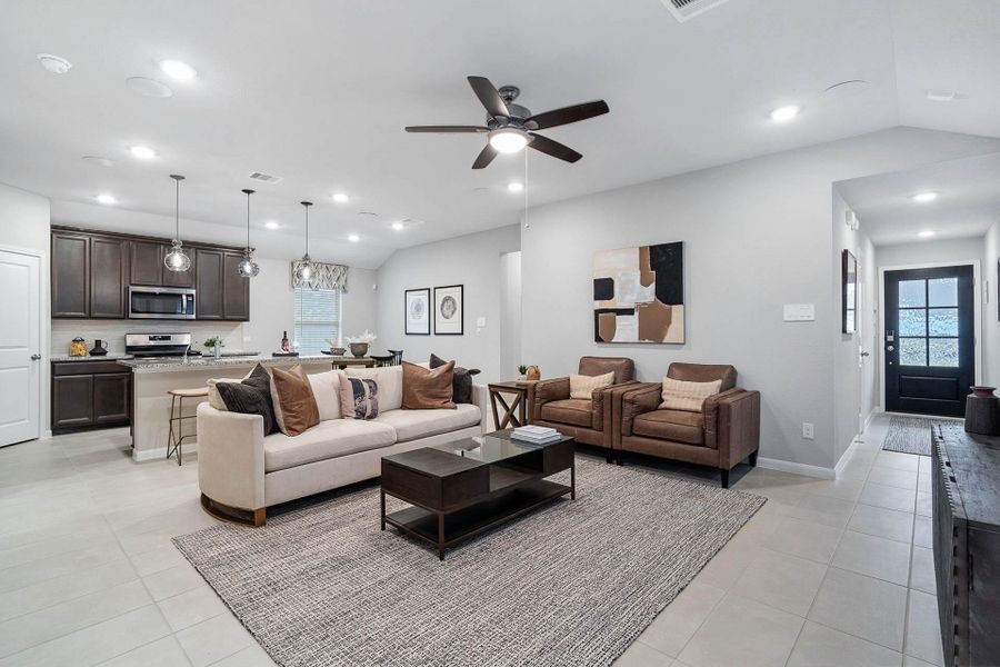 Enjoy fluid movement between the comfortable living room and the well-appointed kitchen/dining area, featuring sleek tile flooring and abundant natural light throughout the cohesive space.