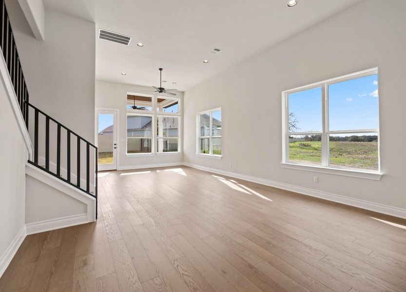 Unfurnished living room featuring visible vents, ceiling fan, baseboards, wood finished floors, and stairs Unfurnished living room featuring visible vents, ceiling fan, baseboards, wood finished floors, and stairs
