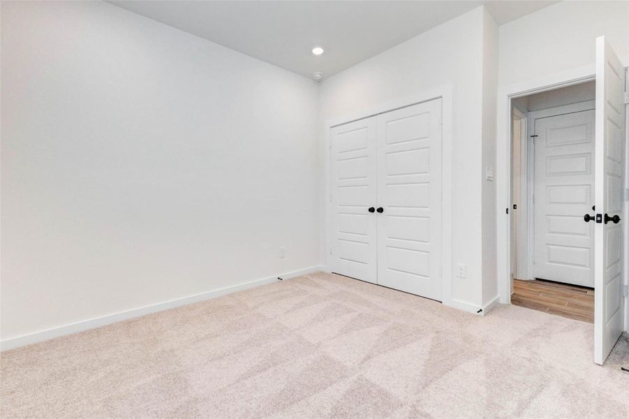 Another secondary bedroom showcases its spacious layout and bright, airy feel. The room offers ample wall space for furniture placement and décor, while the nearby doorway provides easy access to the rest of the home. With its neutral palette and comfortable design, this space is ready to be personalized.
