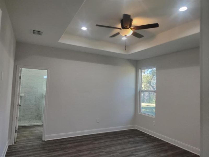 with a tray ceiling, dark wood-type flooring, ceiling fan, and recessed lighting with a tray ceiling, dark wood-type flooring, ceiling fan, and recessed lighting