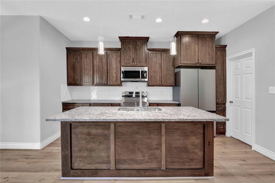 Love this kitchen! Island for additional seating with sink. Refrigerator included! Electric range, microwave and tons of cabinets. That door leads to the utility room and pantry.