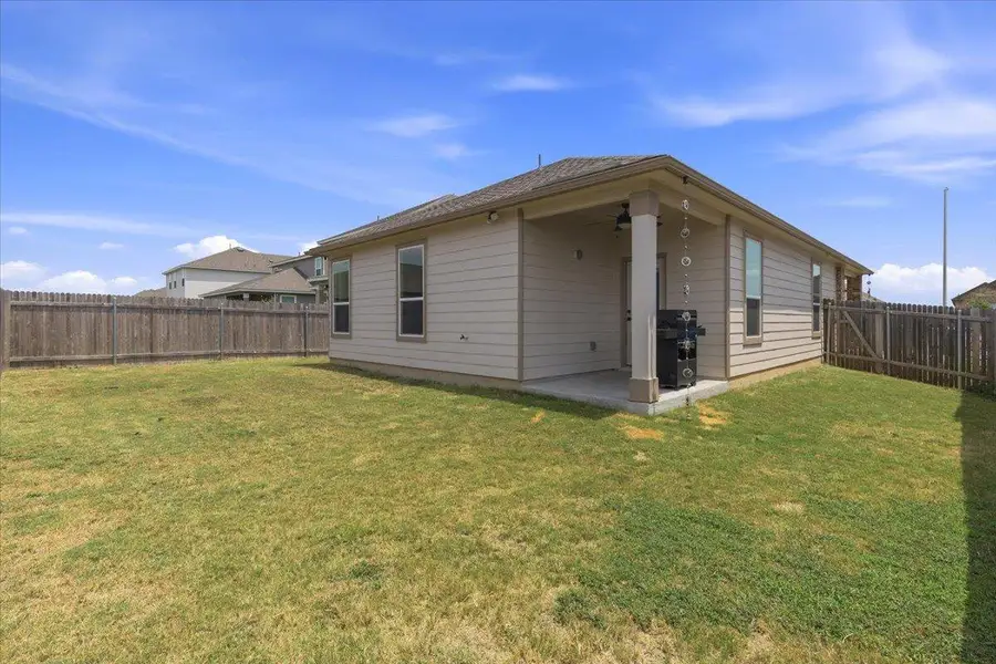 A private backyard oasis featuring a well-maintained lawn and a covered patio, perfect for outdoor living.