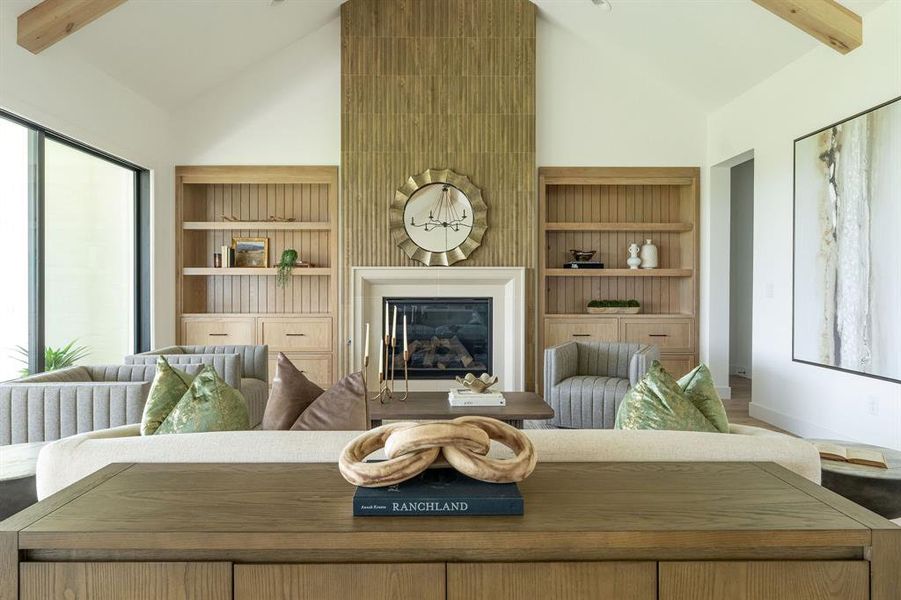 Living room featuring beamed ceiling, plenty of natural light, high vaulted ceiling, a glass covered fireplace, and built in features Living room featuring beamed ceiling, plenty of natural light, high vaulted ceiling, a glass covered fireplace, and built in features