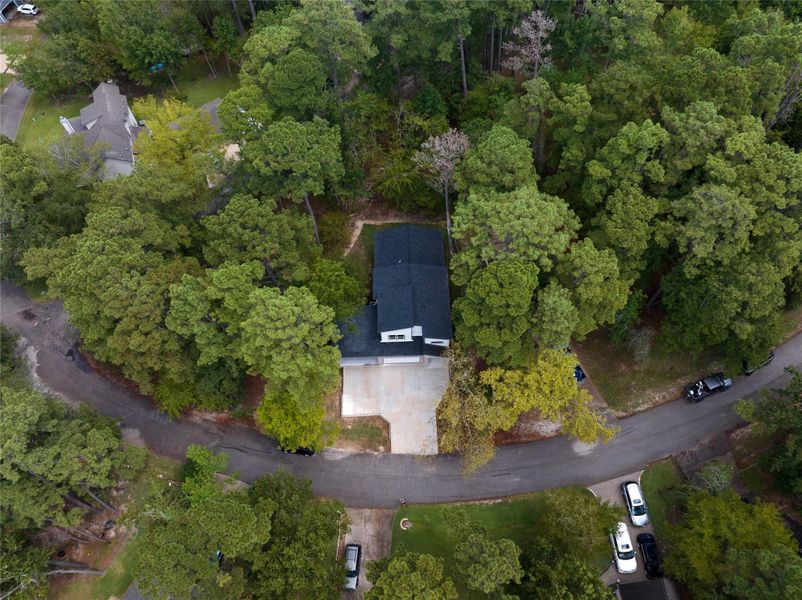 This aerial view showcases a beautiful home in a serene lakeside community, nestled within a lush, forested setting. With a private dock and direct access to the water, the house offers a peaceful and secluded living experience, combining comfort and tranquility in the perfect lakeside retreat.