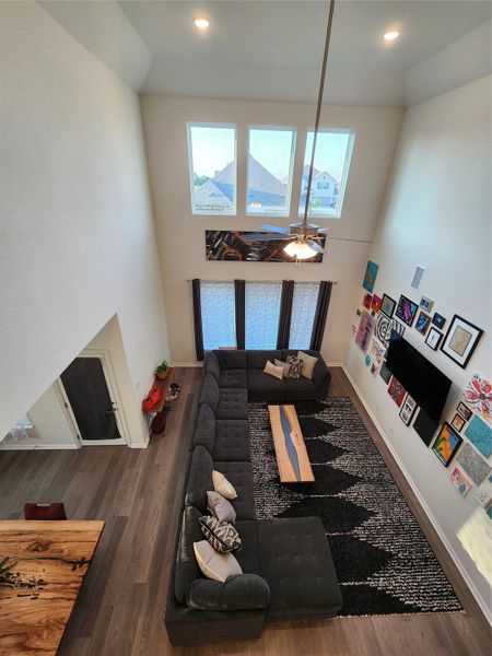 A grand living space features soaring ceilings, abundant natural light, and richly textured hardwood flooring.