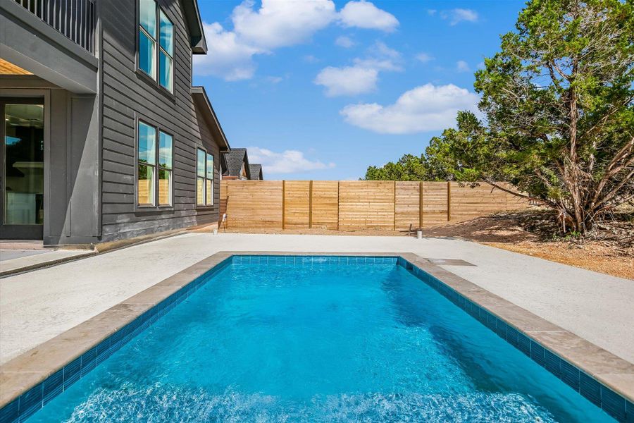 A private, in-ground swimming pool provides a refreshing escape in this tranquil backyard setting.
