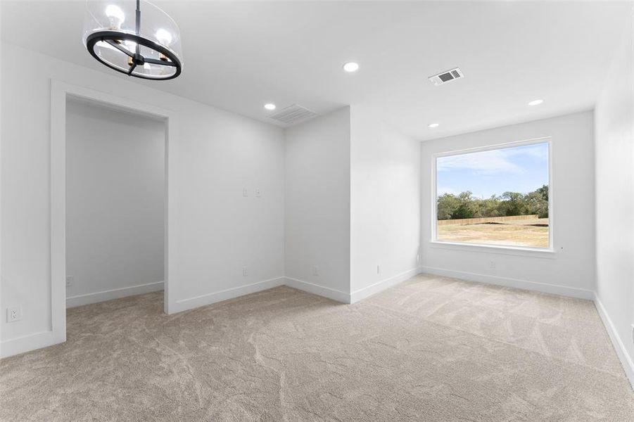 Empty room with light colored carpet, recessed lighting, and a chandelier