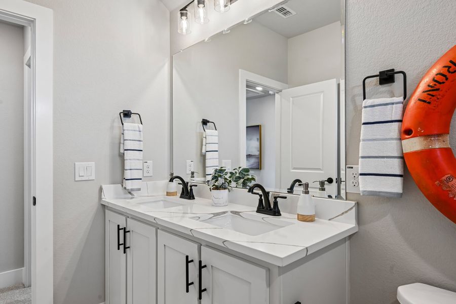 Bathroom with double vanity, white quartz countertops, gray cabinets, and large mirror with pendant lights above