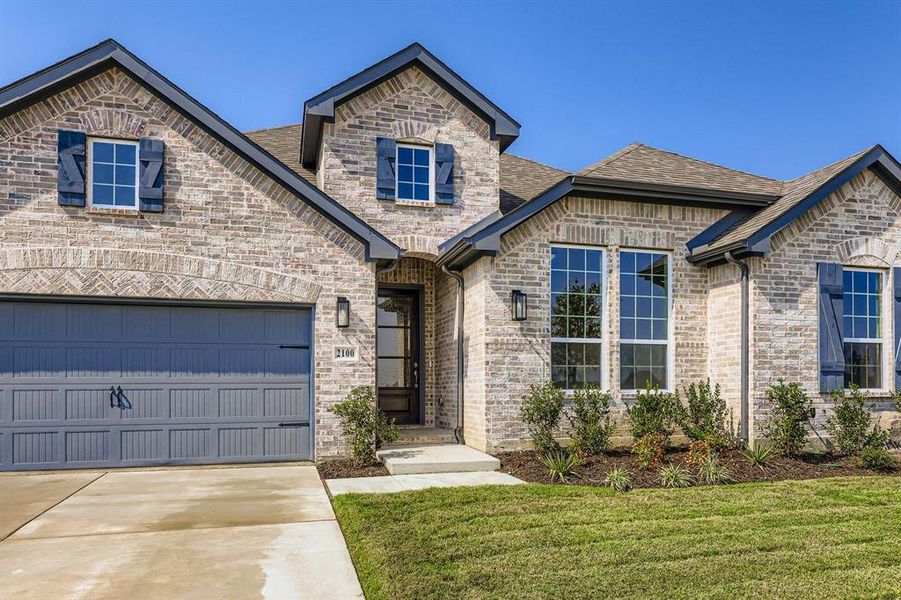 View of front facade featuring driveway, brick siding, an attached garage, a front lawn, and roof with shingles