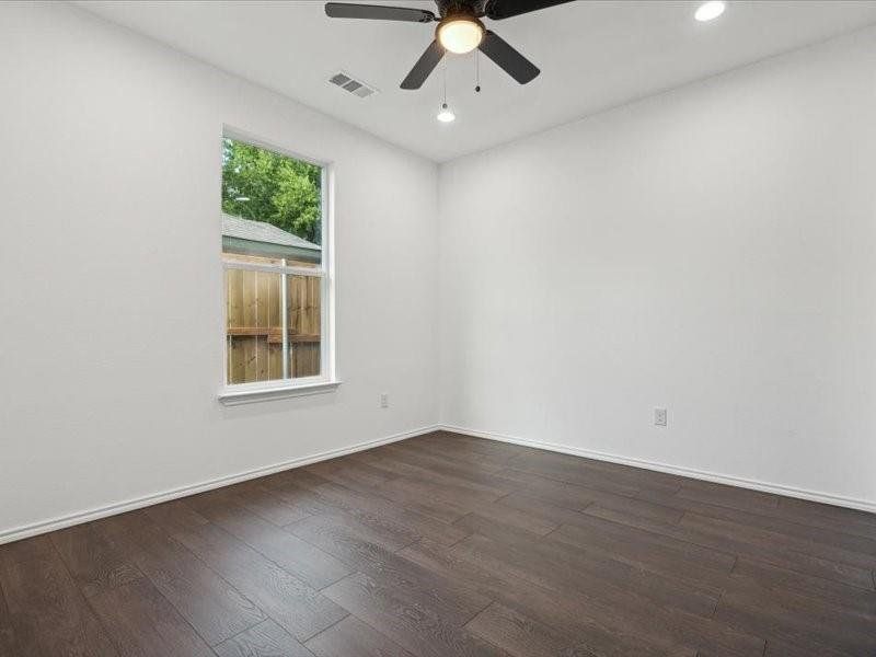 Unfurnished room featuring dark wood-type flooring and ceiling fan