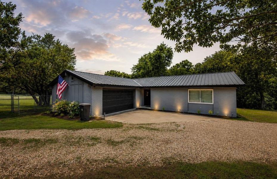 Contemporary-style residence featuring a metal roof, light gray exterior siding, and a dark garage door