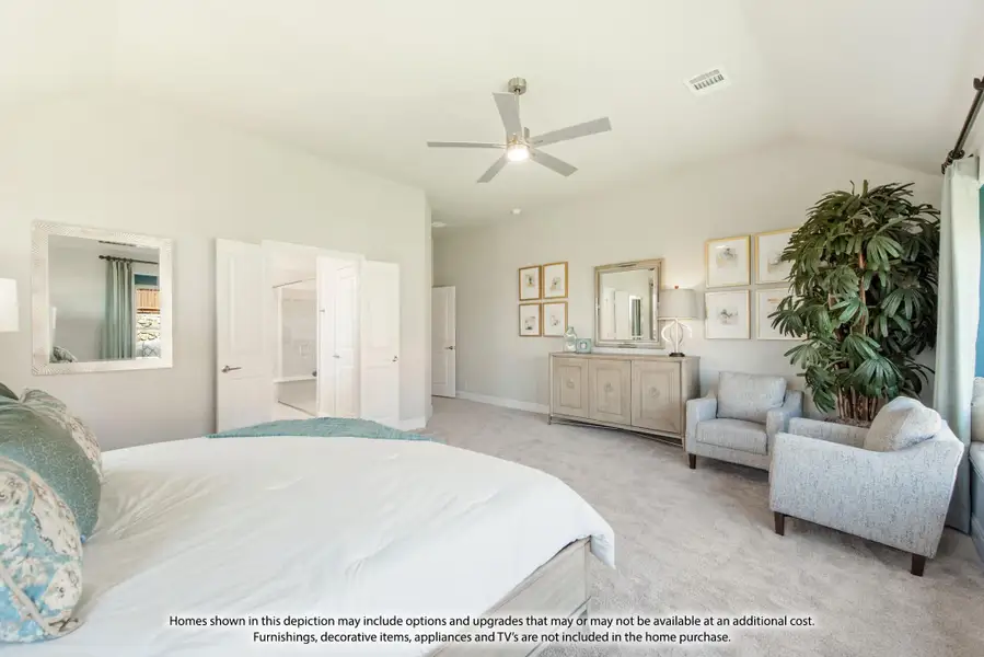 Spacious master bedroom with ceiling fan, carpet flooring, seating area, and open ensuite bathroom door Spacious master bedroom with ceiling fan, carpet flooring, seating area, and open ensuite bathroom door