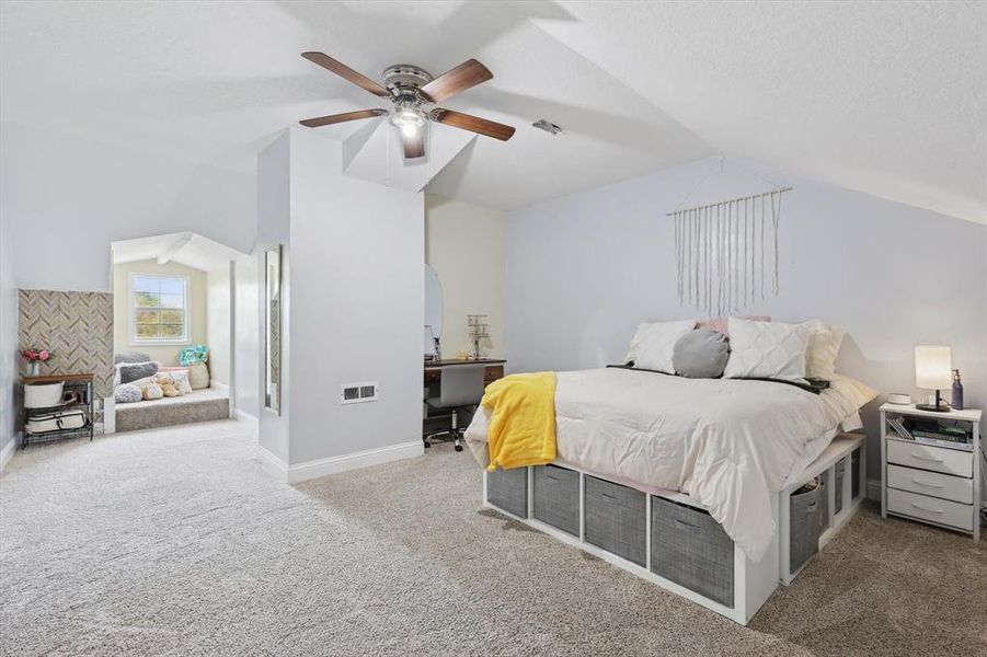 Carpeted bedroom with ceiling fan and vaulted ceiling