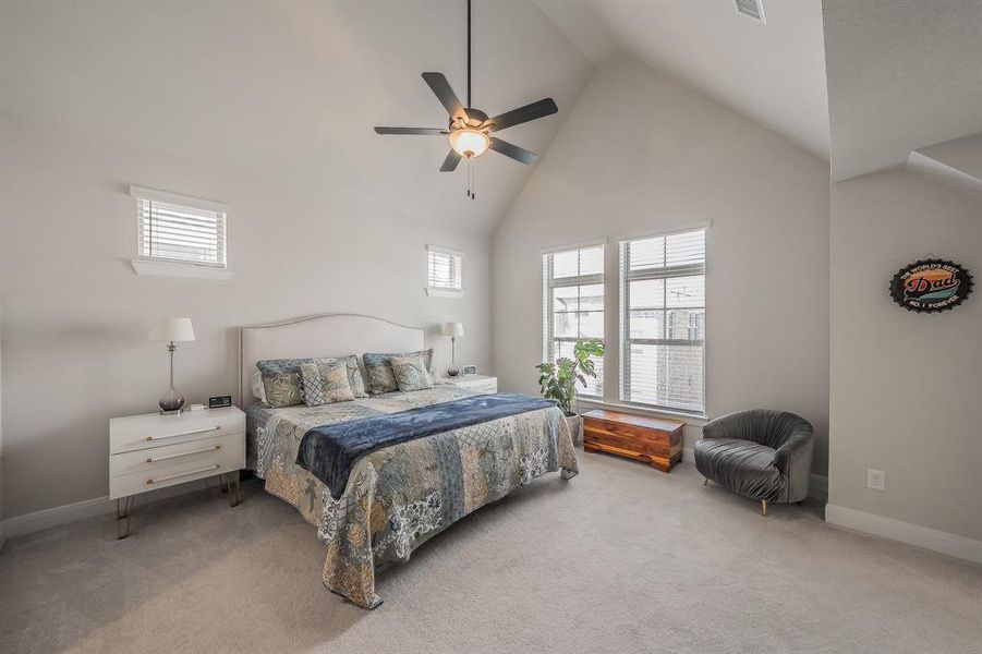 Bedroom featuring high vaulted ceiling, carpet flooring, multiple windows, and a ceiling fan
