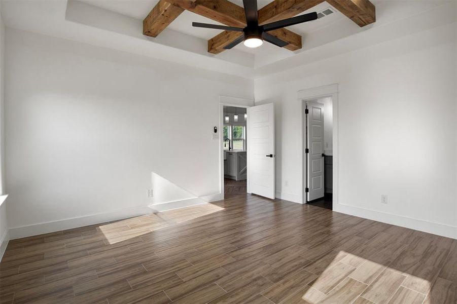 Unfurnished room featuring ceiling fan, beam ceiling, and dark wood-type flooring