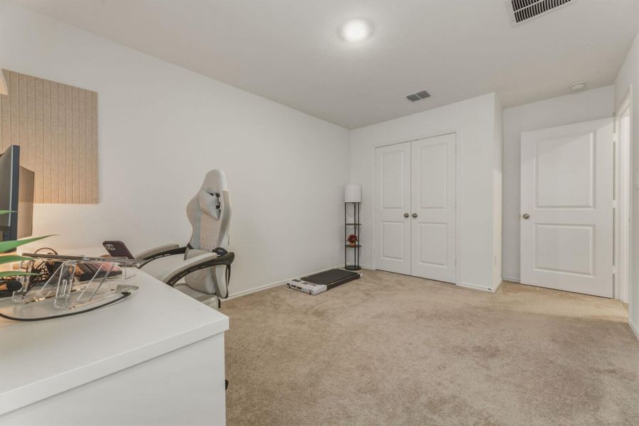 This room features light-colored carpeting, white walls, and a recessed ceiling light