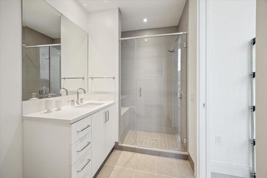 Secondary bedroom en-suite bathroom with generously sized step in shower, porcelain tiles and neutral colors.