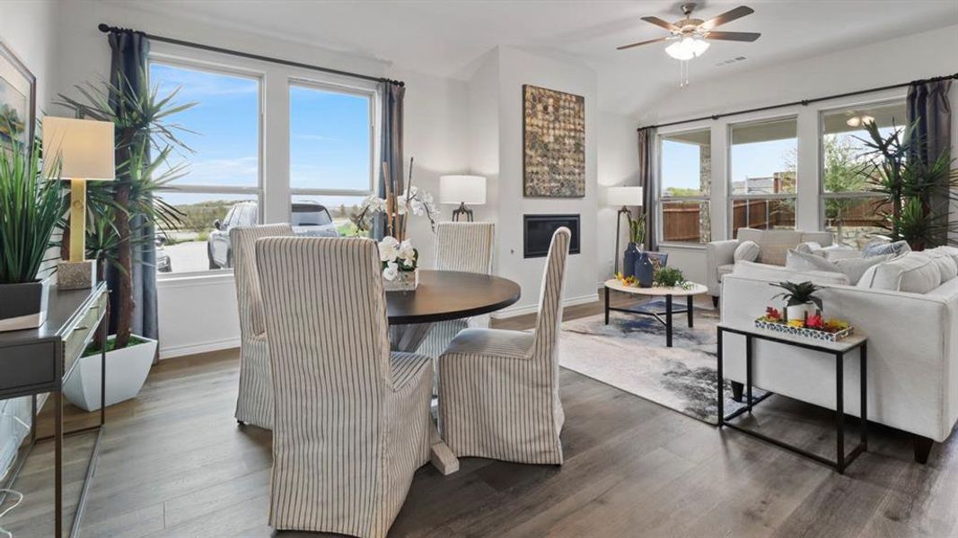 Dining area with hardwood / wood-style flooring, a fireplace, ceiling fan, and vaulted ceiling