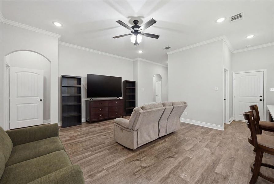 Living area with arched walkways, recessed lighting, a ceiling fan, crown molding, and wood finished floors