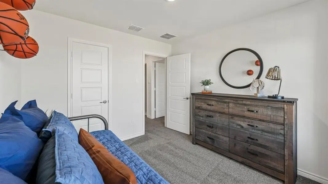 Spacious room featuring neutral carpeting, white walls, and a modern dresser with black hardware