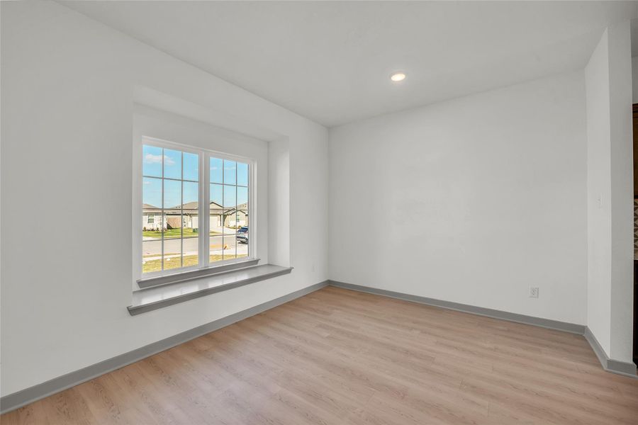 Unfurnished room with a residential view, light wood-style floors, and recessed lighting