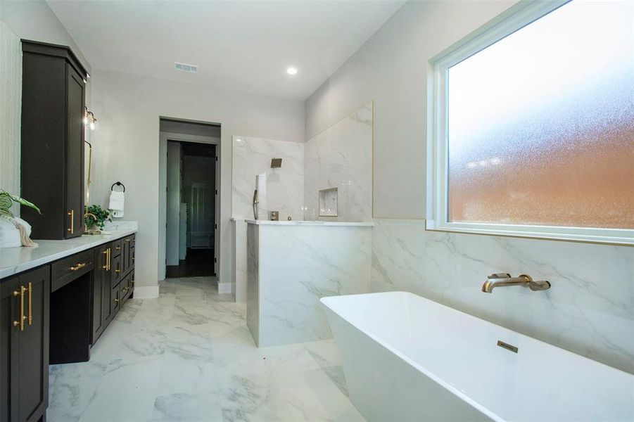 Bathroom with vanity, a bathtub, and tile walls