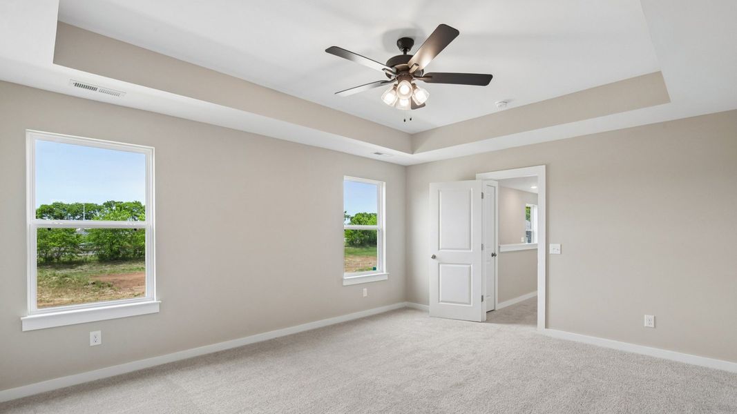 Bedroom with tray ceiling, windows, and entrance to primary bedroom Bedroom with tray ceiling, windows, and entrance to primary bedroom