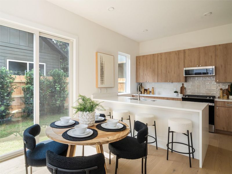 Modern kitchen featuring wood-finish cabinetry, a white countertop island, stainless steel appliances, and a tile backsplash