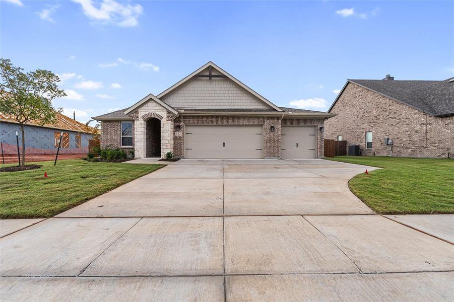 View of front of property featuring a front yard, driveway, a garage, and brick siding View of front of property featuring a front yard, driveway, a garage, and brick siding