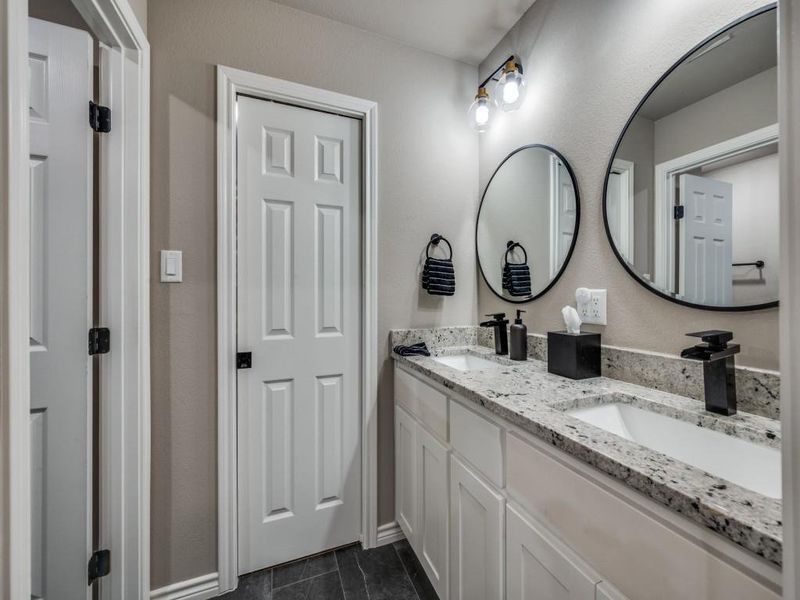 Full bathroom featuring double vanity and baseboards Full bathroom featuring double vanity and baseboards