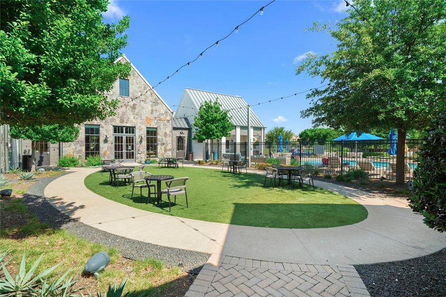 Outdoor courtyard with stone-clad building, manicured lawn, and paved walkways