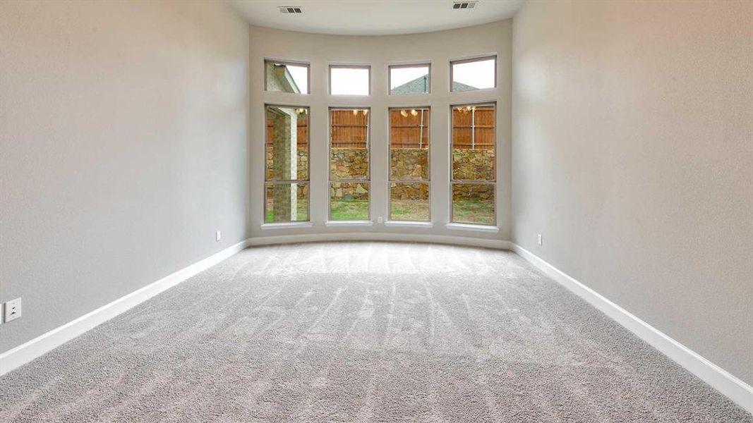 Carpeted empty room featuring a towering ceiling and a wealth of natural light