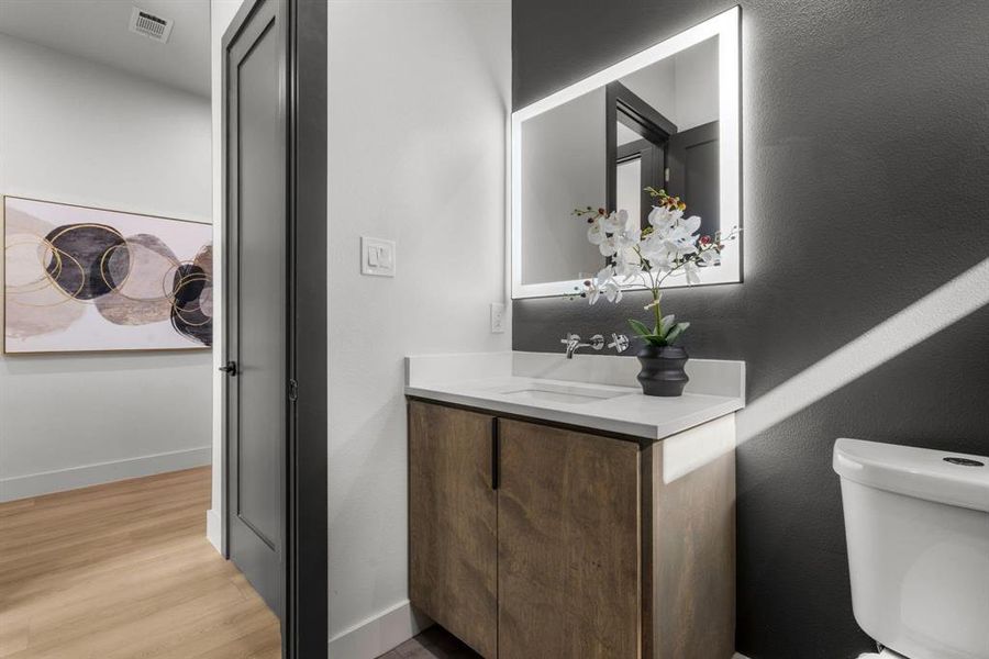 Half bathroom featuring vanity, light wood finished floors, and a textured wall