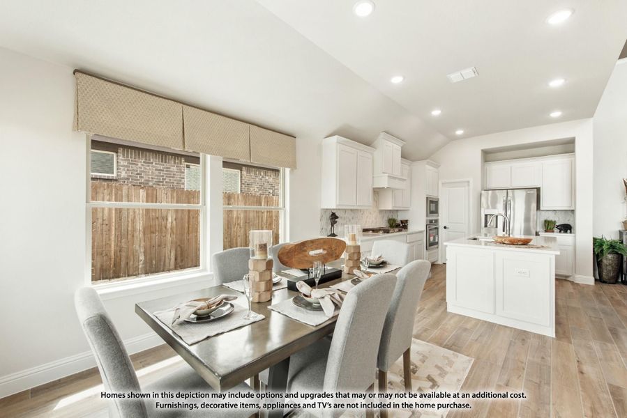 Open dining area with set table and chairs flowing into white kitchen with island and hardwood floors