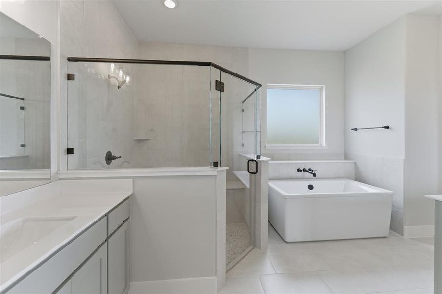 Full bathroom with vanity, a stall shower, a freestanding bath, and light tile patterned floors