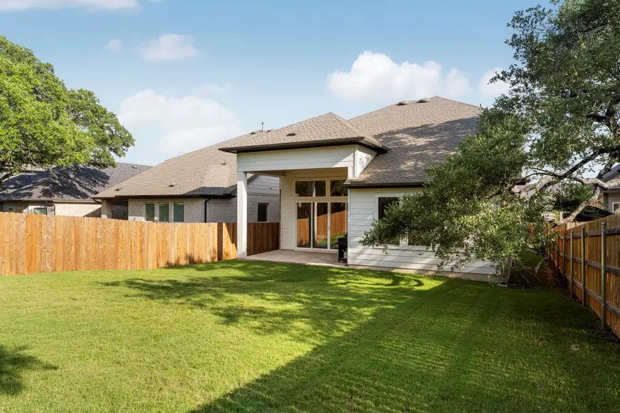 A generous lawn and privacy fencing enclose the inviting rear elevation of this home.