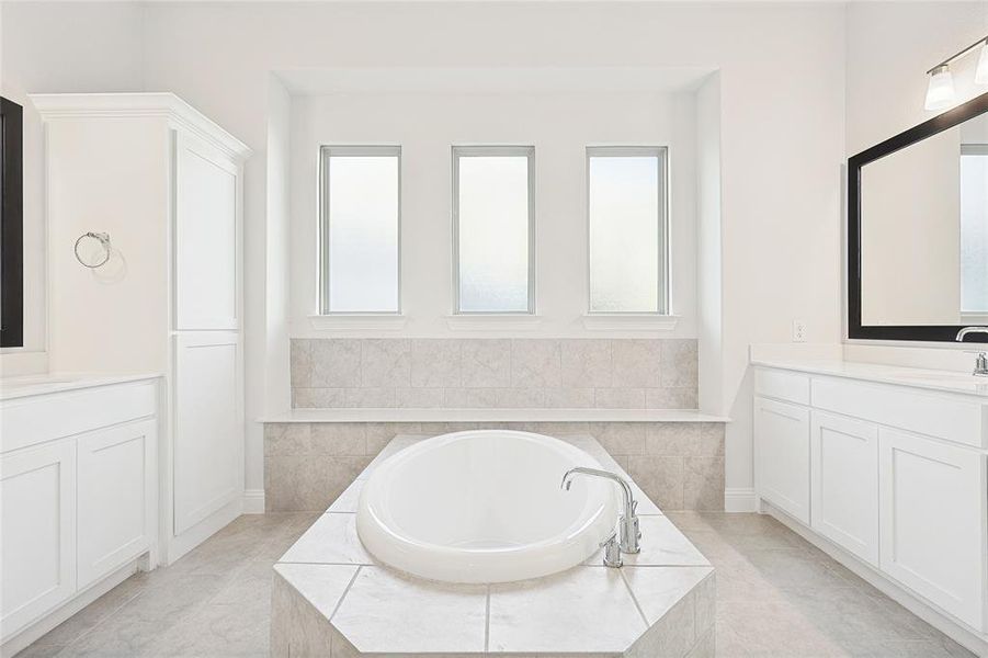 Bathroom with vanity, tile patterned floors, and tiled tub