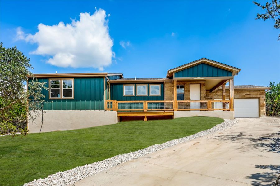 View of front facade featuring board and batten siding, a front lawn, driveway, a garage, and a porch