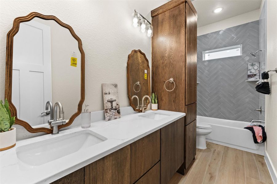 Bathroom featuring light wood-type flooring, double vanity, and shower / tub combination
