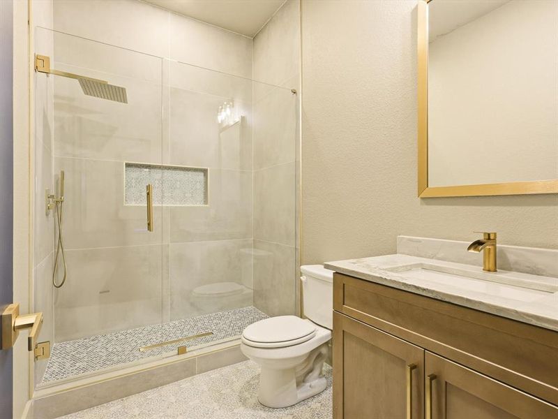 Bathroom with vanity, a stall shower, and a textured wall