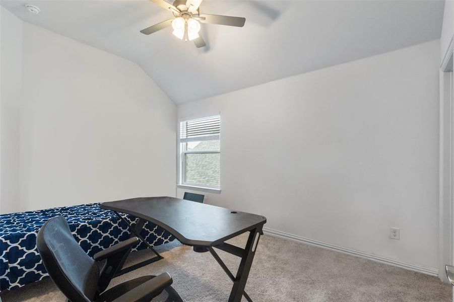 Home office with vaulted ceiling, light colored carpet, and a ceiling fan