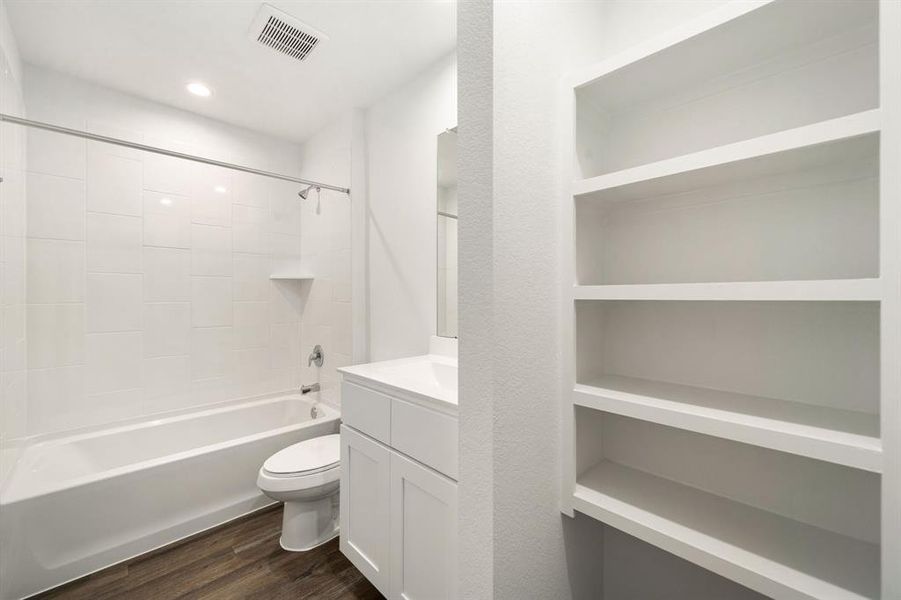 Secondary bathroom features light countertops and cabinets, shower/tub combo with tile surround, large mirror, sleek fixtures and modern finishes, plenty of space to accommodate any visiting family or guests.