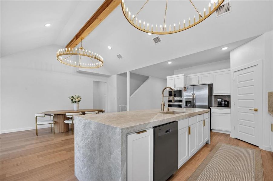 Modern kitchen featuring a large stone-wrapped island with an undermount sink and gooseneck faucet