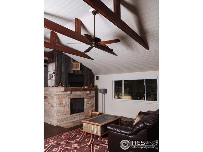 Carriage House living room. Stone fireplace, wood ceiling and beams