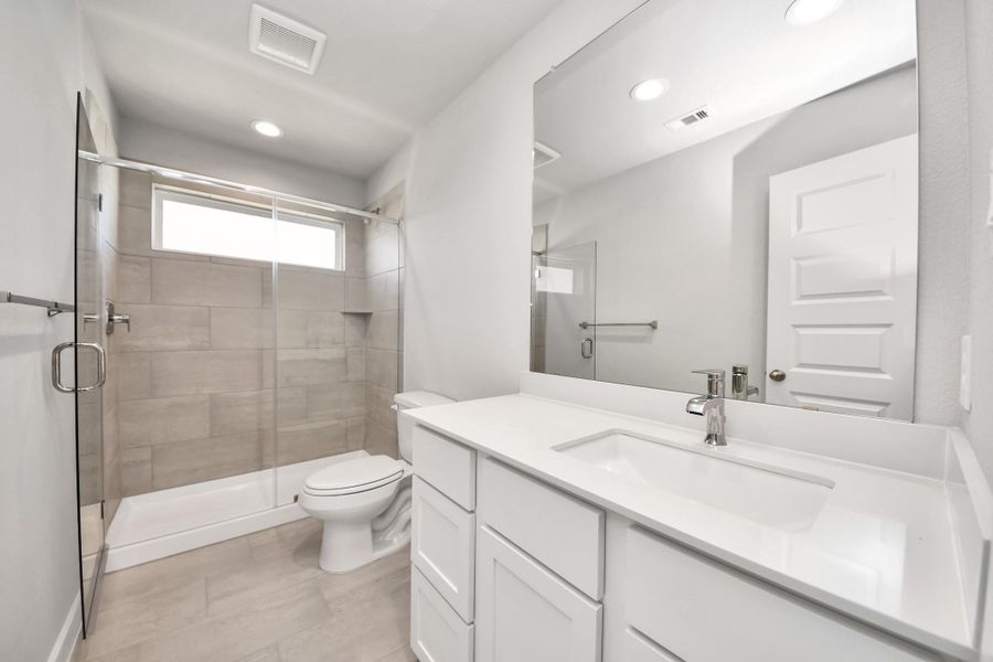 Secondary bath features tile flooring, bath/shower combo with tile surround, light stained wood cabinets, beautiful light countertop. Sample photo of completed home with similar floor plan. Actual colors and selections may vary.